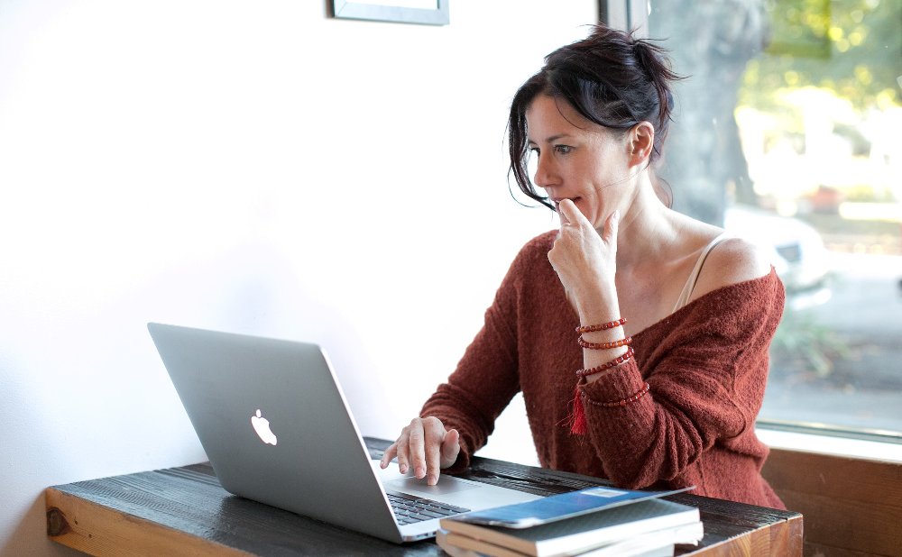 A woman looking to her computer, that symbolizes online therapy in English, in Madrid city.